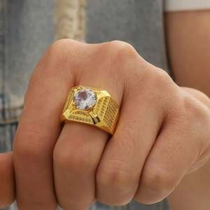 Détail d'une bague de luxe dorée pour homme sertie de cristaux sur fond de tissu denim