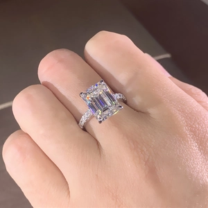 Gros plan d'une bague en diamant simulé taille émeraude avec pavé sur la main