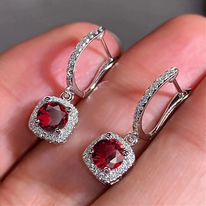 Close-up of red halo earrings with zircon pavé setting and U-shaped hinged ear buckles