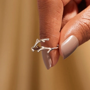 Eleganter silberner Geweih-Ring für Damen, präsentiert an der Hand vor warmem Hintergrund