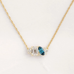 Elegant gold necklace with emerald cut clear stone and blue marquise gemstone
