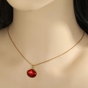 Gouden halsketting met een rode schelphanger gedragen op een model voor een mooie look