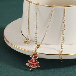 Gouden kerstboom ketting met rood email en kristallen op een stijlvolle mok rand