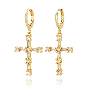 Détail de boucles d'oreilles créoles croix dorées avec sertissage en zircons brillants