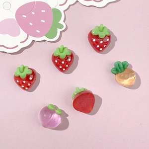 Macro shot of colorful resin strawberry and peach fruit charms for DIY crafts and jewelry