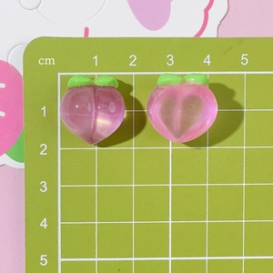 Close-up of translucent pink peach resin charms on a centimeter scale grid mat