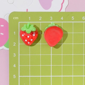 Detailed view of resin strawberry charms with 1.8cm scale on a cutting mat