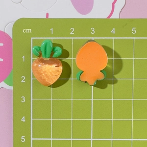 Detail view of transparent orange resin carrot DIY charms with dimensions on a green scale