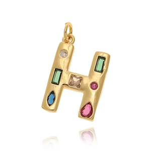 Detalle de colgante letra H bañado en oro con cristales de circonita de colores incrustados