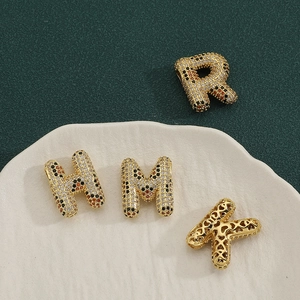 Makroaufnahme von Buchstabenanhängern mit Leoparden-Zirkonia und Herz-Hohlmustern
