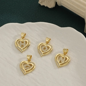 Golden heart-shaped letter pendants with micro-pave cubic zirconia on a green background