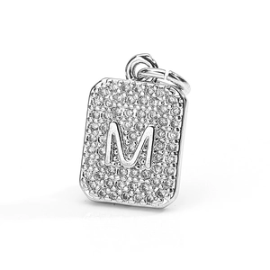 Detailed macro view of silver square pendant with letter M and pavé cubic zirconia stones