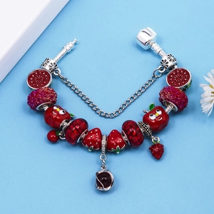 Red crystal beaded snake chain bracelet with strawberry and apple charms on blue background