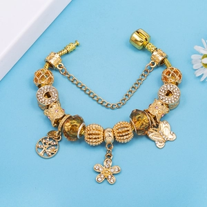 Goldenes Bettelarmband mit Lebensbaum-Anhänger und bernsteinfarbenen Perlen auf Blau