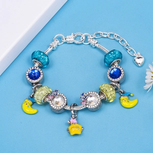Zilveren kralenarmband met blauwe glazen kralen en gele maan- en sterhangers op blauw