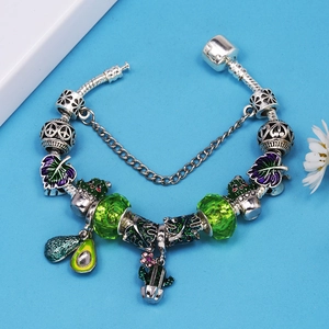 Silbernes Charm-Armband mit grünen Perlen, Avocado- und Kaktusanhänger auf blauem Grund