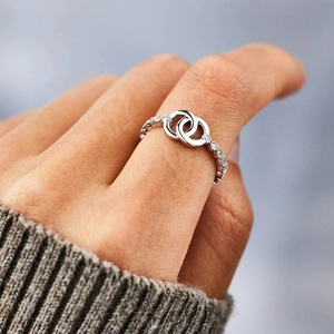 Close-up of a silver intertwined double-circle ring with sparkling diamond accents on hand