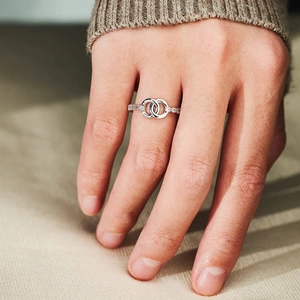 Close-up of interlocking silver rings with micro-pave crystals on a female finger