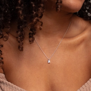 Détail du collier argenté avec pendentif en zircon rectangulaire sur le cou du mannequin