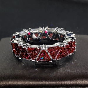 Macro shot of silver ring with full set triangle-cut red zircon stones on dark texture