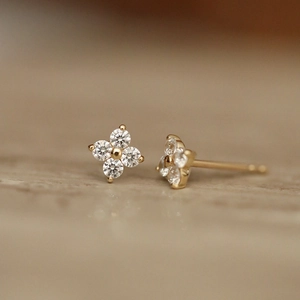 Minimalist gold four-leaf clover stud earrings with clear sparkling gemstones