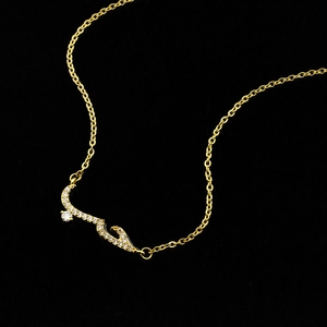 Detailed macro view of gold-tone Arabic calligraphy pendant necklace with sparkling zircons