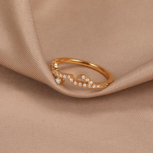 Detailed macro view of a rose gold wavy band ring set with sparkling white zircon stones