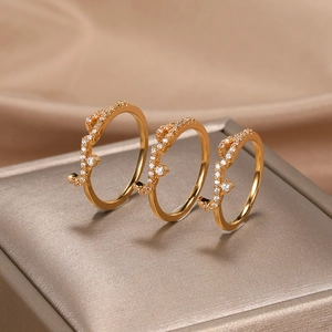 Detailed view of three rose gold rings with cubic zirconia on champagne silk background