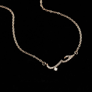 Rose gold Arabic Love necklace with sparkling cubic zirconia on a dark background
