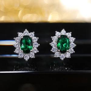 Macro detail of sunburst stud earrings with emerald green gemstone and micro zircon petals