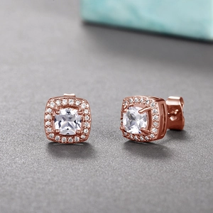 Macro shot of rose gold square stud earrings featuring cushion cut zircon with halo setting