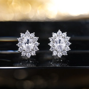 Macro shot of silver sunflower stud earrings with micro-paved zircons on a reflective base