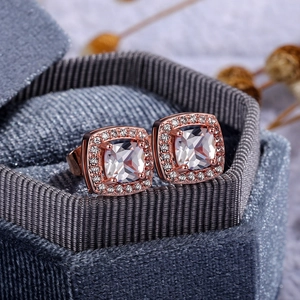 Macro shot of rose gold halo stud earrings with square-cut zircon in a luxury jewelry box