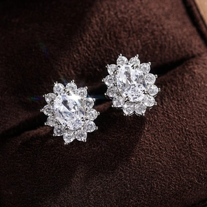 Macro shot of oval-cut zircon halo stud earrings set in polished silver on velvet
