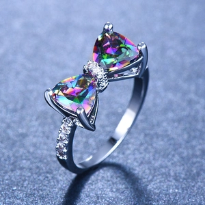 Bowknot ring with colorful triangle stones and white crystals on blue background