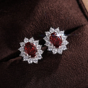 Macro detail of sunflower stud earring featuring an oval ruby-red stone and white zircons
