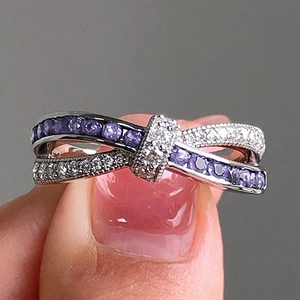 Elegant silver bow ring with purple and white cubic zirconia on a female finger