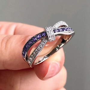 Detailed view of ribbon bow ring with purple and white micro-pave crystals on silver band