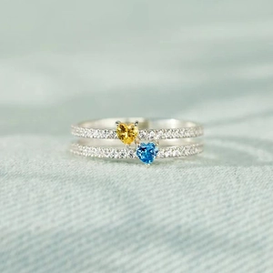 Makro-Detail eines Doppel-Rings mit blauem und gelbem Herz-Edelstein und Zirkonia