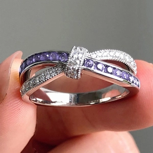 Elegant silver knot ring with purple and white zircon stones shown on a hand