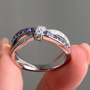 Detail of cross band ring with purple gemstone and pavé diamonds in two-tone finish