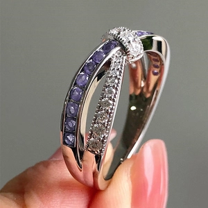 Detailed shot of criss-cross ring with purple gems and clear zircons on a silver band