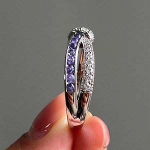 Macro view of crossover ring with purple and white stones and milgrain detailing