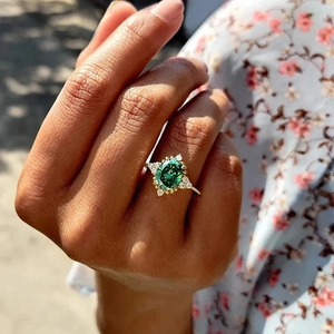 Detailed view of a vintage gold ring with an oval emerald green stone and white diamonds
