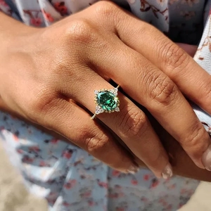 Detail of a vintage-style gold ring with an oval green emerald and white accent stones
