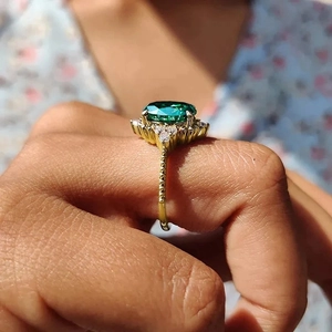 Detailed side view of vintage gold ring with emerald green gem and halo diamonds