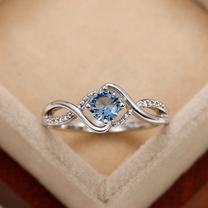 Macro detail of wave-shaped silver ring featuring a round blue stone and pavé accents