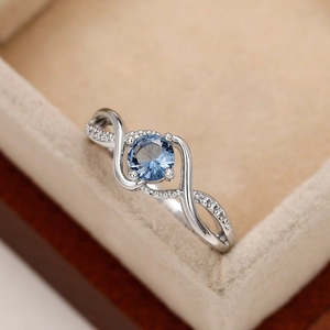 Macro shot of wavy silver ring with a round blue gemstone and white zircon accents