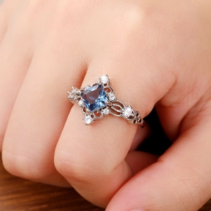 Detailed close-up of vintage ring with princess cut blue gemstone and ornate silver carving