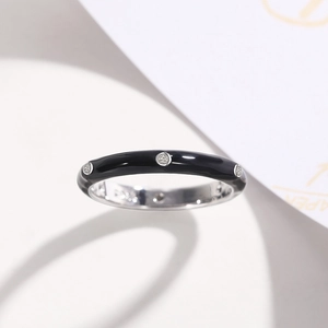 Close-up of slim silver ring featuring black enamel inlay and zircon stone settings